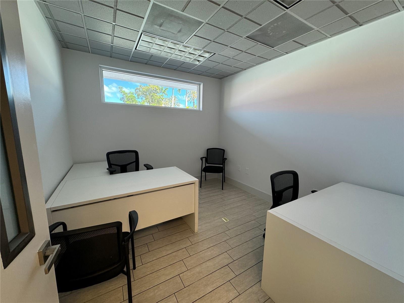 A small office with white desks, black mesh chairs, tile flooring, and a horizontal window — 2719 Hollywood Boulevard, Hollywood FL 33020, HOLLYWOOD, FL