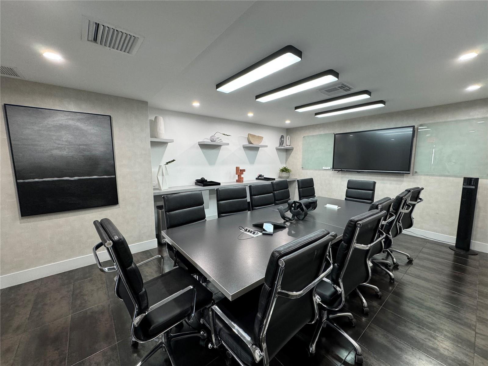 A modern conference room features a long table, black leather chairs, and wall-mounted television — 2719 Hollywood Boulevard, Hollywood FL 33020, HOLLYWOOD, FL