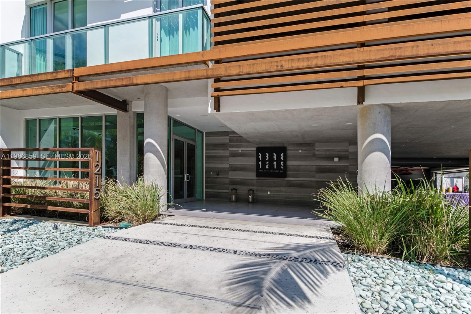 The exterior entrance features a concrete walkway, a metal address sign, and horizontal wood slats — 1215 West Ave # 402, Miami Beach FL 33139, MIAMI BEACH, FL