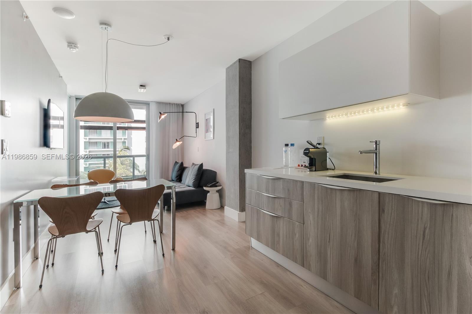 A modern studio apartment features a kitchenette, dining area, and living space with balcony access — 1215 West Ave # 402, Miami Beach FL 33139, MIAMI BEACH, FL