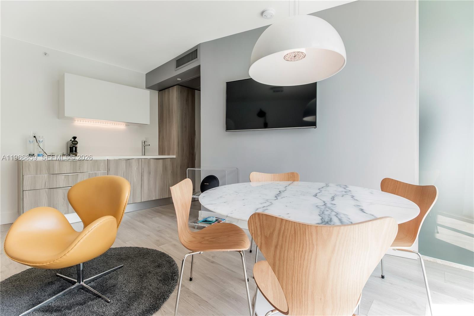 A dining area features a marble table, wooden chairs, and a nearby kitchenette — 1215 West Ave # 402, Miami Beach FL 33139, MIAMI BEACH, FL