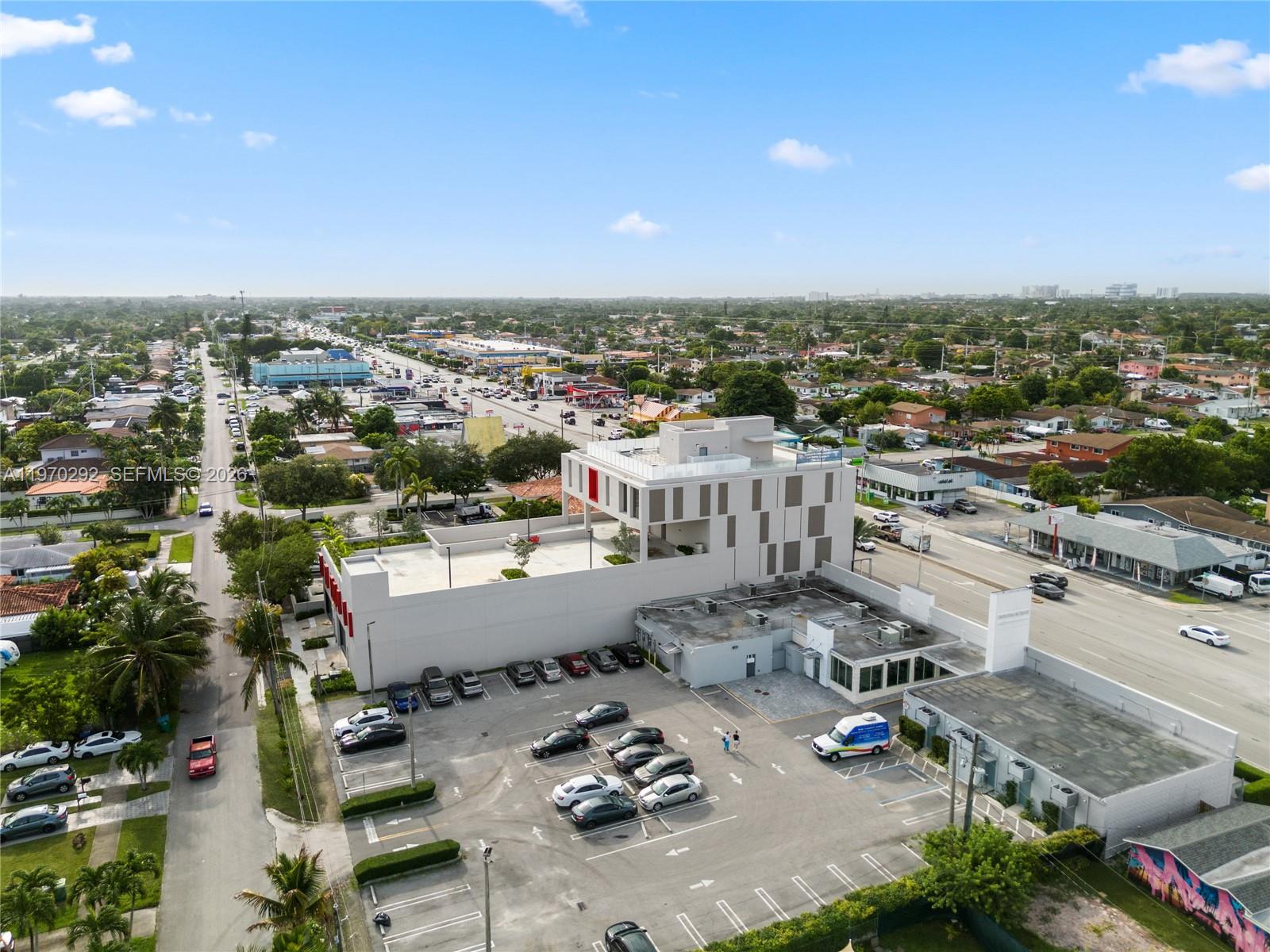 An aerial view shows a modern multi-story building with a parking lot and surrounding neighborhood — 8966 Bird Road, Miami FL 33165, MIAMI, FL