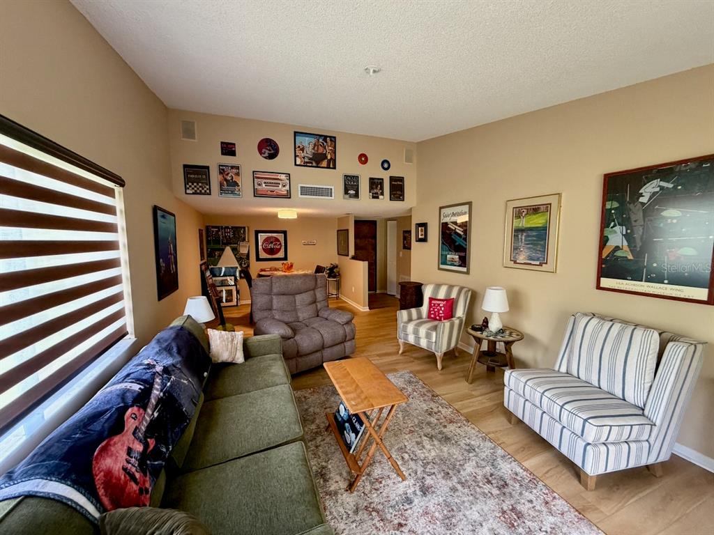 A living room features a green sofa, patterned armchairs, a coffee table, and wall art — 13604 S VILLAGE DRIVE UNIT 314, TAMPA, FL