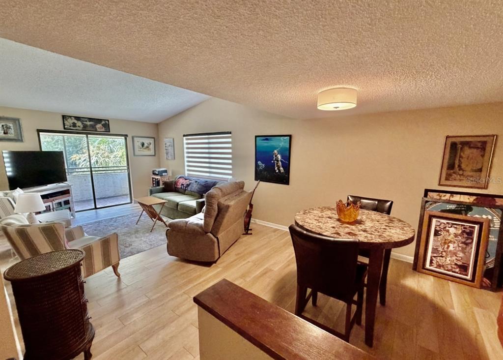 A living and dining area features light wood flooring, a vaulted ceiling, and a balcony — 13604 S VILLAGE DRIVE UNIT 314, TAMPA, FL