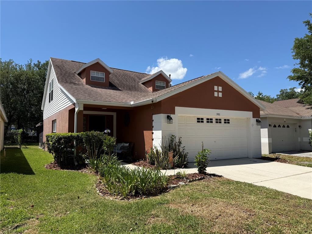 A two-story house with a terracotta-colored facade, white garage door, and a front lawn — 5901 WRENWATER DRIVE, LITHIA, FL