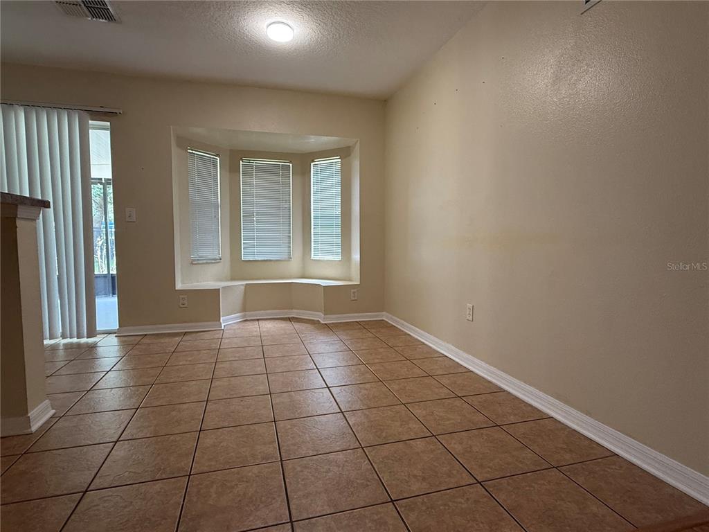 A dining area features tile flooring, a bay window with built-in seating, and sliding glass doors — 5901 WRENWATER DRIVE, LITHIA, FL
