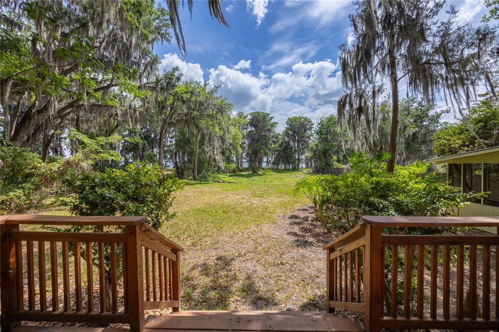 A wooden deck overlooks a grassy backyard with mature trees draped in Spanish moss — 7305 NE 222ND STREET, MELROSE, FL