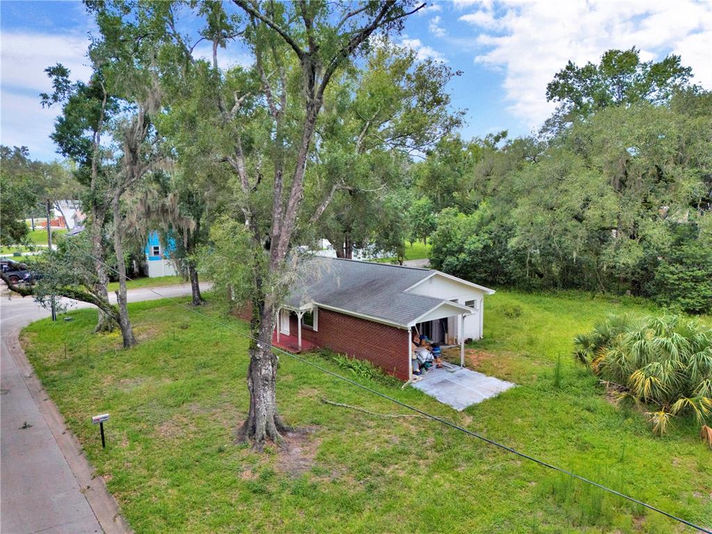 An aerial view shows a single-story brick house with a carport surrounded by trees — 11916 DAVIS ROAD, TAMPA, FL