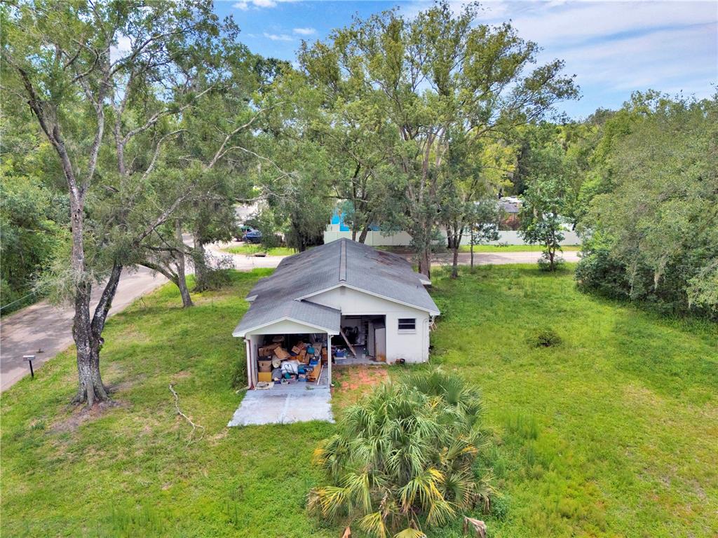 An aerial view shows a detached garage with an open bay filled with clutter — 11916 DAVIS ROAD, TAMPA, FL
