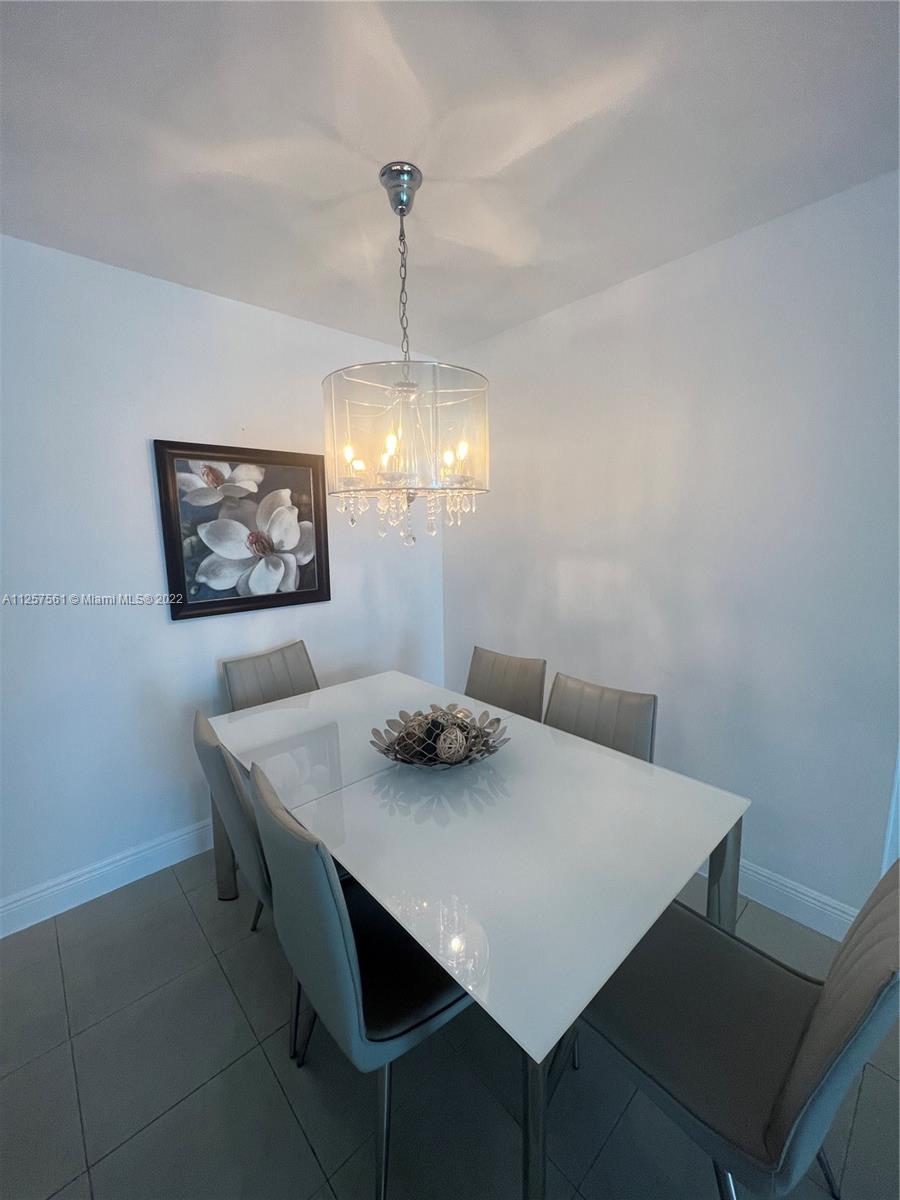 A dining room features a white table, six gray chairs, and a crystal drum chandelier — 5151 Collins Ave # 725, Miami Beach FL 33140, MIAMI BEACH, FL