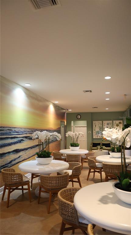A room with several round tables, wicker chairs, and a large beach mural on the wall — 108 FOREST HILLS DRIVE, REDINGTON SHORES, FL