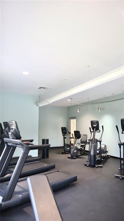 A gym room features several treadmills and elliptical machines on a dark floor — 108 FOREST HILLS DRIVE, REDINGTON SHORES, FL