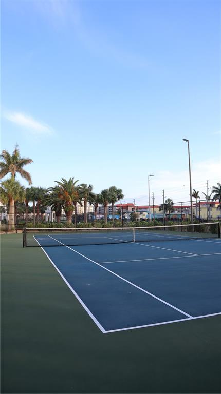 A blue and green outdoor tennis court is surrounded by palm trees and a fence — 108 FOREST HILLS DRIVE, REDINGTON SHORES, FL