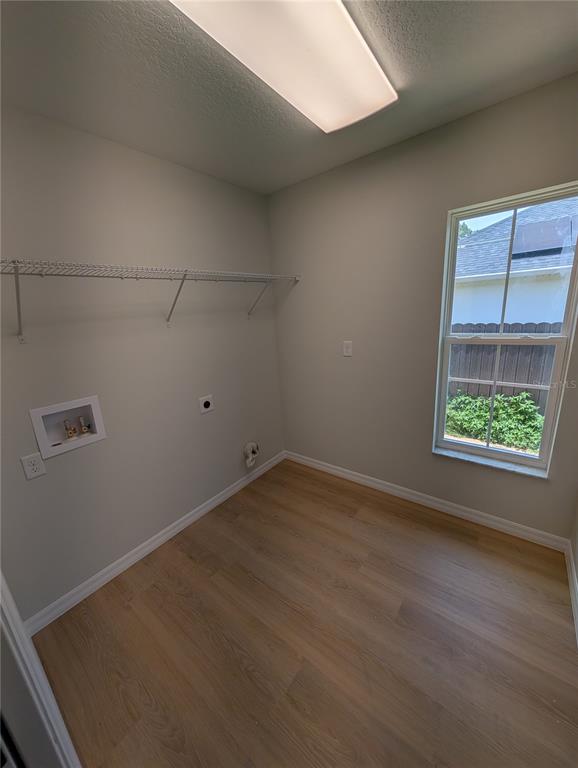 A laundry room with light wood-look flooring, a wire shelf, and a window — 4244 SW 157TH COURT SW, OCALA, FL