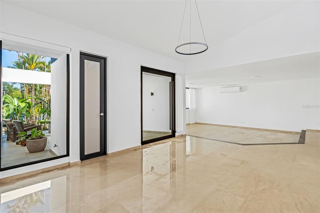A bright, minimalist room features polished marble floors, black-framed glass doors, and a modern pendant light — 3 GARDEN HILLS ESTATES UNIT 12, GUAYNABO, PR