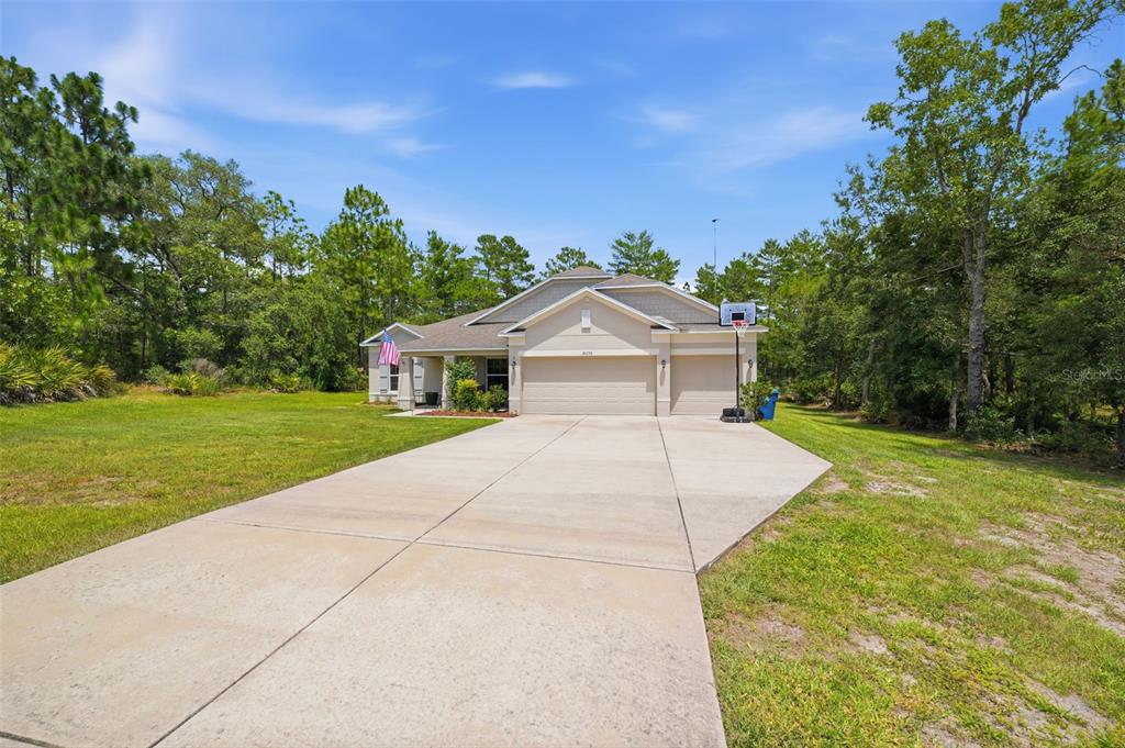 A single-story house with a beige exterior, a three-car garage, and a concrete driveway — 18296 MABERLY ROAD, WEEKI WACHEE, FL