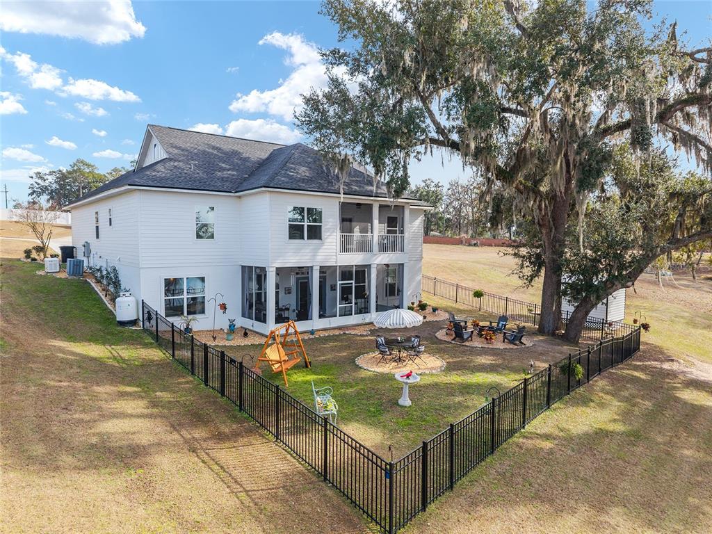 A two-story white house with a screened porch and fenced backyard featuring a large tree — 292 SW OLD CYPRESS WAY, LAKE CITY, FL