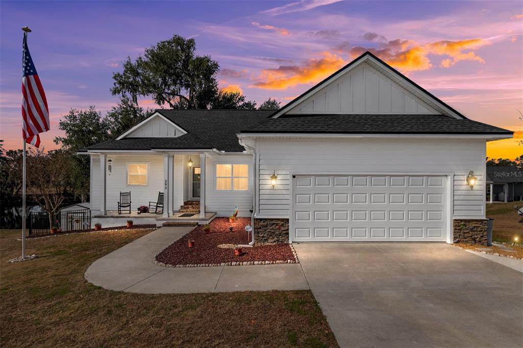 A white house with a two-car garage, a front porch, and an American flag — 292 SW OLD CYPRESS WAY, LAKE CITY, FL