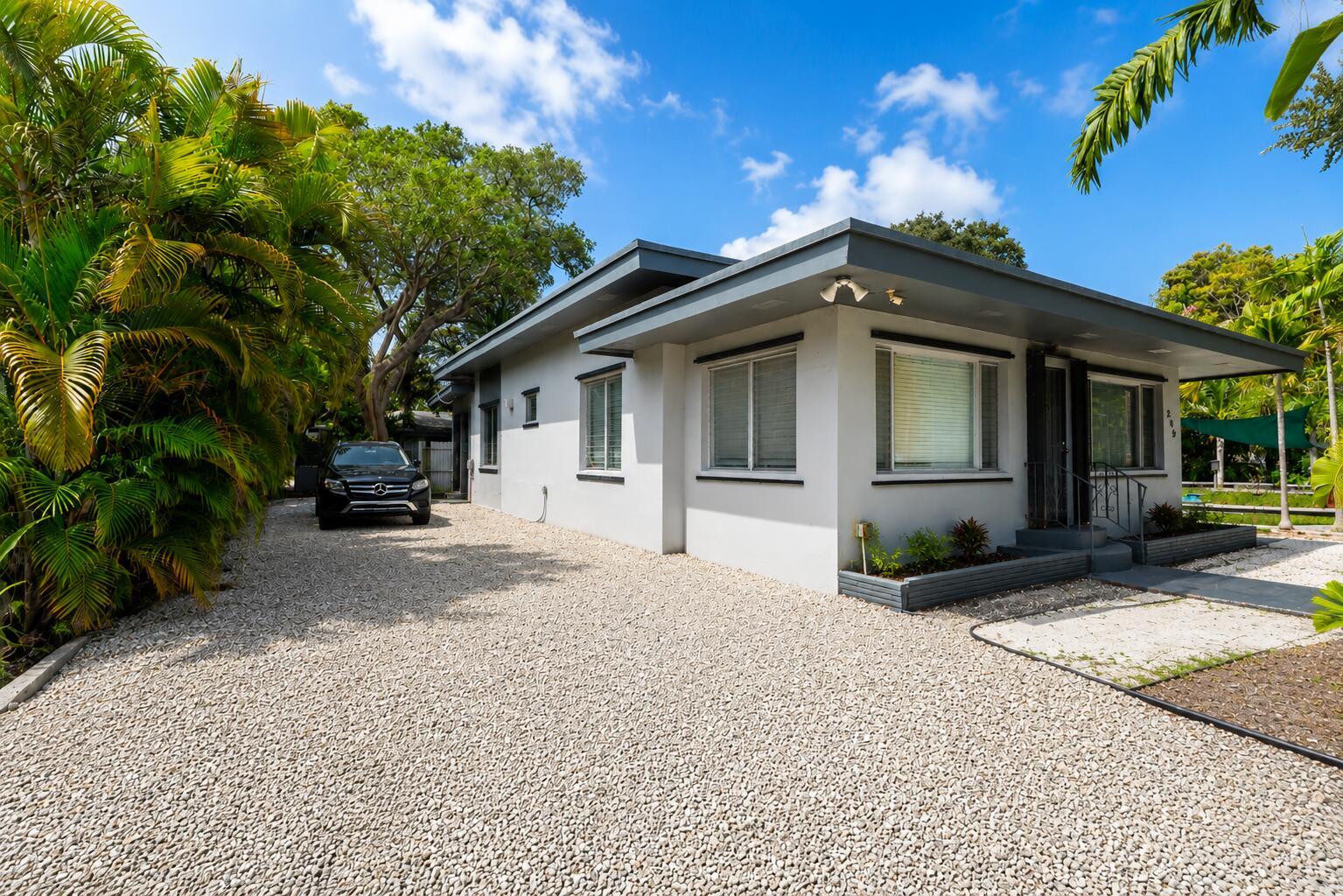 A single-story house with a gravel driveway, gray trim, and palm trees under a blue sky — 249 SW 14th Street # 4, Dania Beach FL 33004, DANIA BEACH, FL