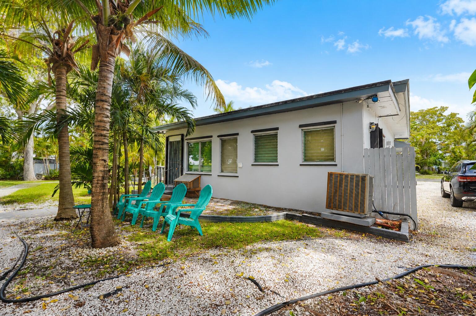A white single-story house with four teal chairs on a gravel yard under palm trees — 249 SW 14th Street # 4, Dania Beach FL 33004, DANIA BEACH, FL