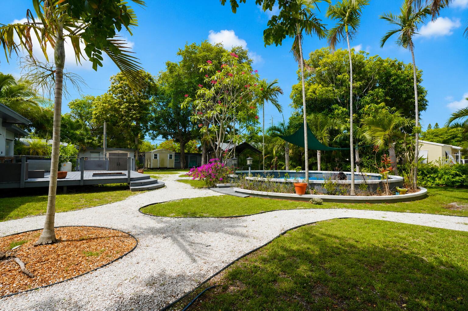 A backyard features a gravel path, a swimming pool with a shade sail, and landscaping — 249 SW 14th Street # 4, Dania Beach FL 33004, DANIA BEACH, FL