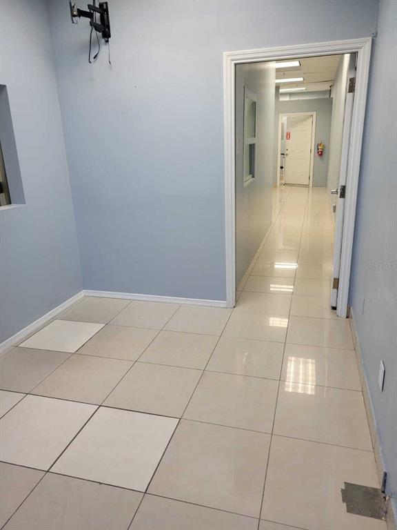 A tiled room leads into a hallway with a white door and a fire extinguisher — 1901 S JOHN YOUNG PARKWAY UNIT 103, KISSIMMEE, FL