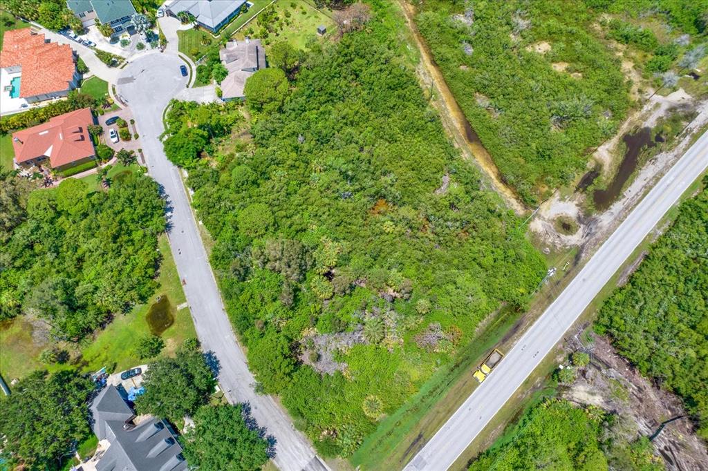 An aerial view shows a vacant, wooded lot situated between a residential street and road — OSCEOLA COURT NE, ST PETERSBURG, FL