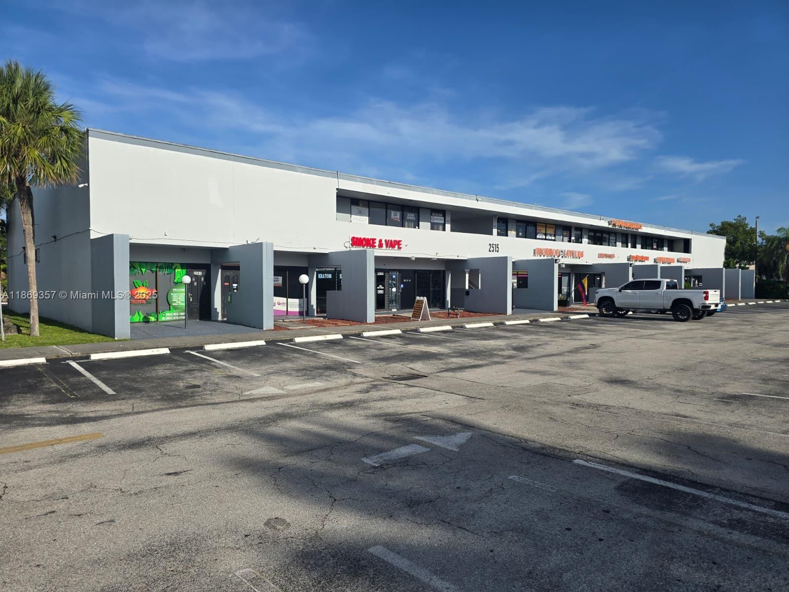 A low-rise commercial strip mall features multiple storefronts and a large paved parking lot — 2501 N State Road 7 # 215, Margate FL 33063, MARGATE, FL