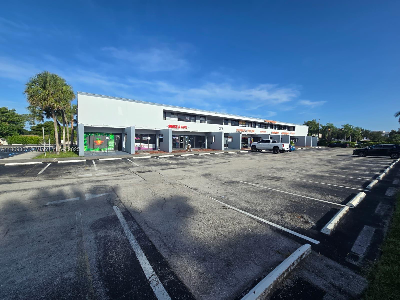 A low-rise commercial strip mall with a parking lot under a clear blue sky — 2501 N State Road 7 # 215, Margate FL 33063, MARGATE, FL