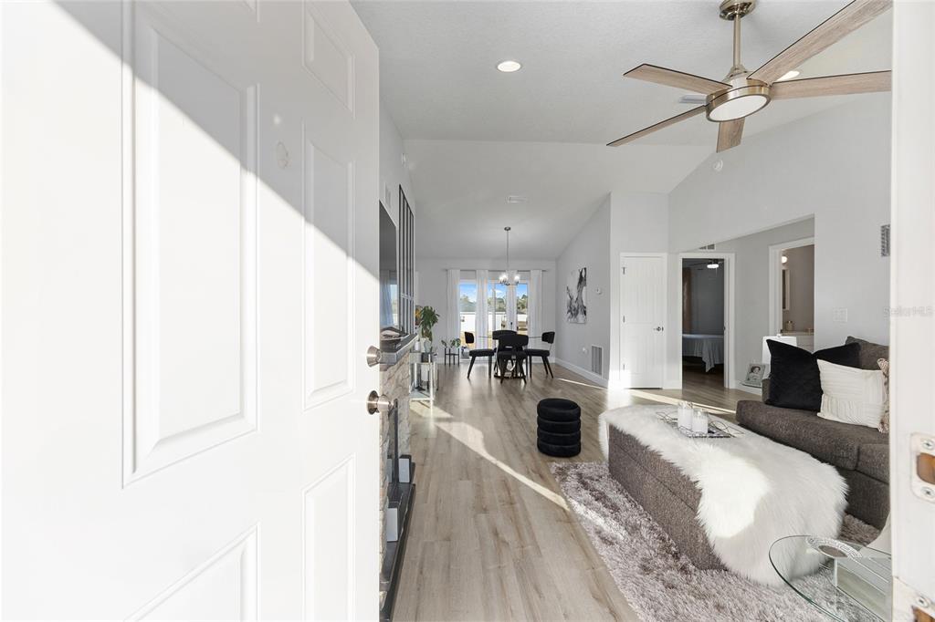 A view from an open doorway into a living room with light wood flooring — 3597 SW 151ST AVENUE, OCALA, FL
