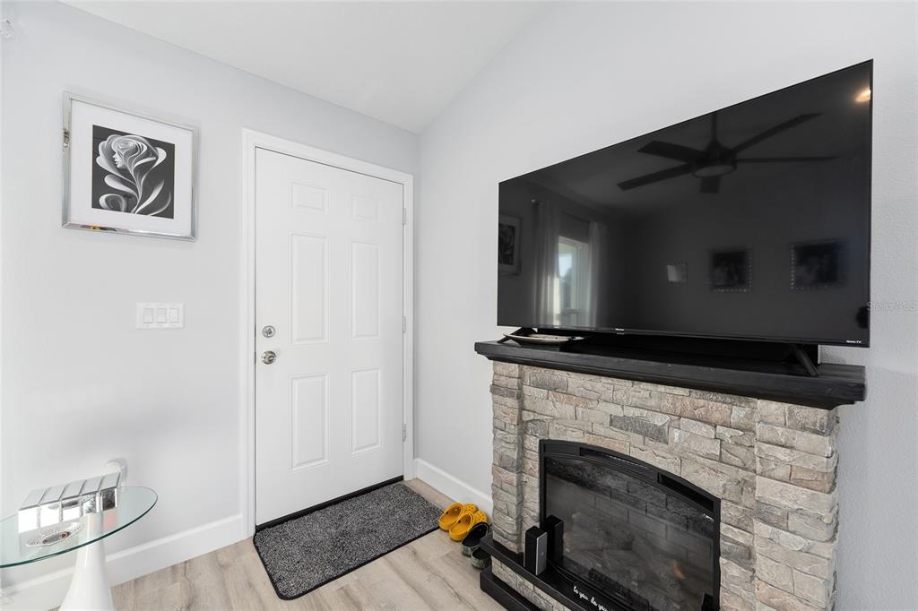 A living room features a stone fireplace, a wall-mounted television, and a white entry door — 3597 SW 151ST AVENUE, OCALA, FL