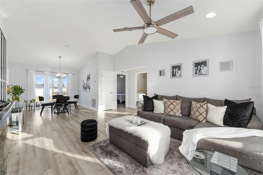 A living room with light wood flooring, a grey sectional sofa, and a dining area — 3597 SW 151ST AVENUE, OCALA, FL