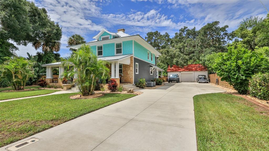 A two-story house with teal siding and a stone foundation features a long concrete driveway — 508 FAULKNER STREET, NEW SMYRNA BEACH, FL