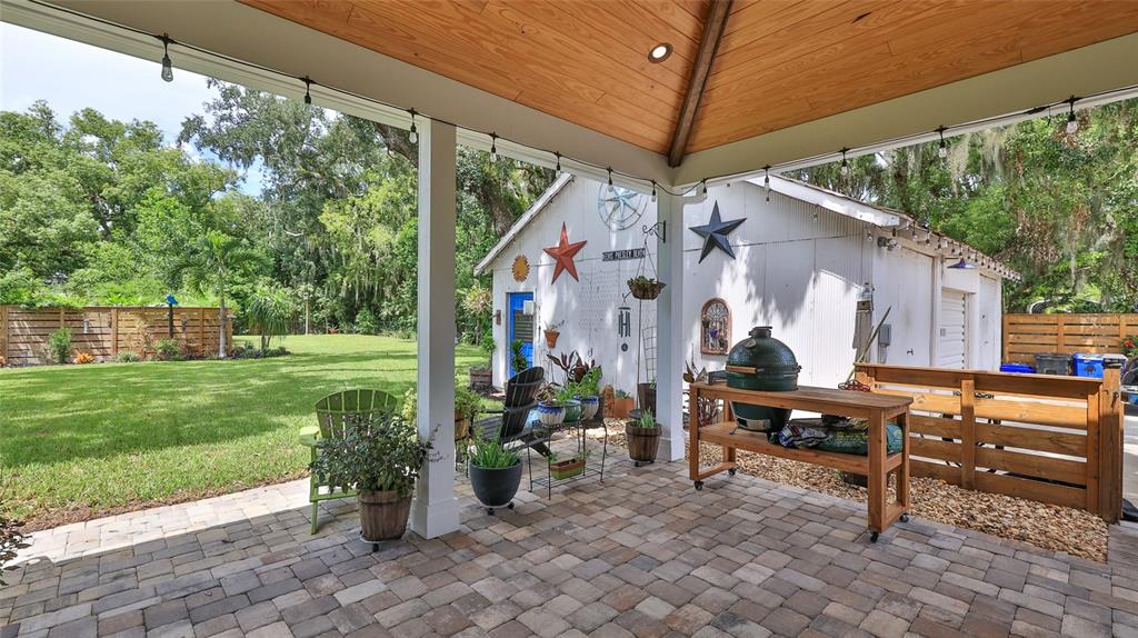 A covered patio with brick pavers, a wooden grill station, and a view of the yard — 508 FAULKNER STREET, NEW SMYRNA BEACH, FL