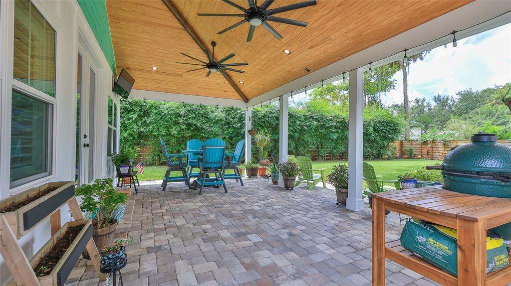 A covered patio features a wood-paneled ceiling, ceiling fans, stone pavers, and outdoor furniture — 508 FAULKNER STREET, NEW SMYRNA BEACH, FL