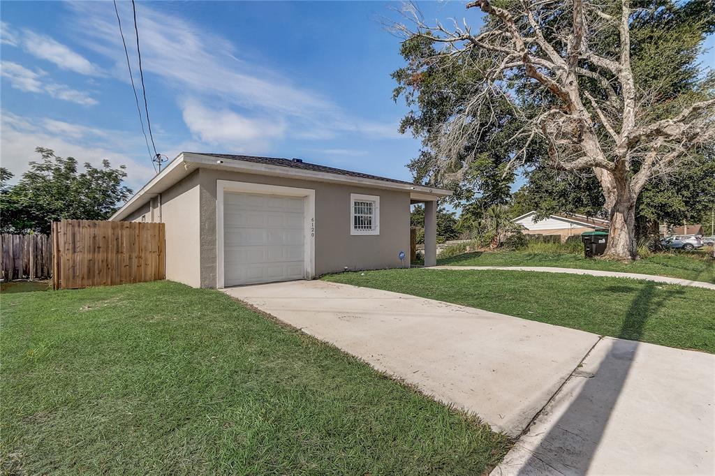 A single-story detached garage with a concrete driveway and a wooden fence on the left — 6120 DENSON DRIVE, ORLANDO, FL