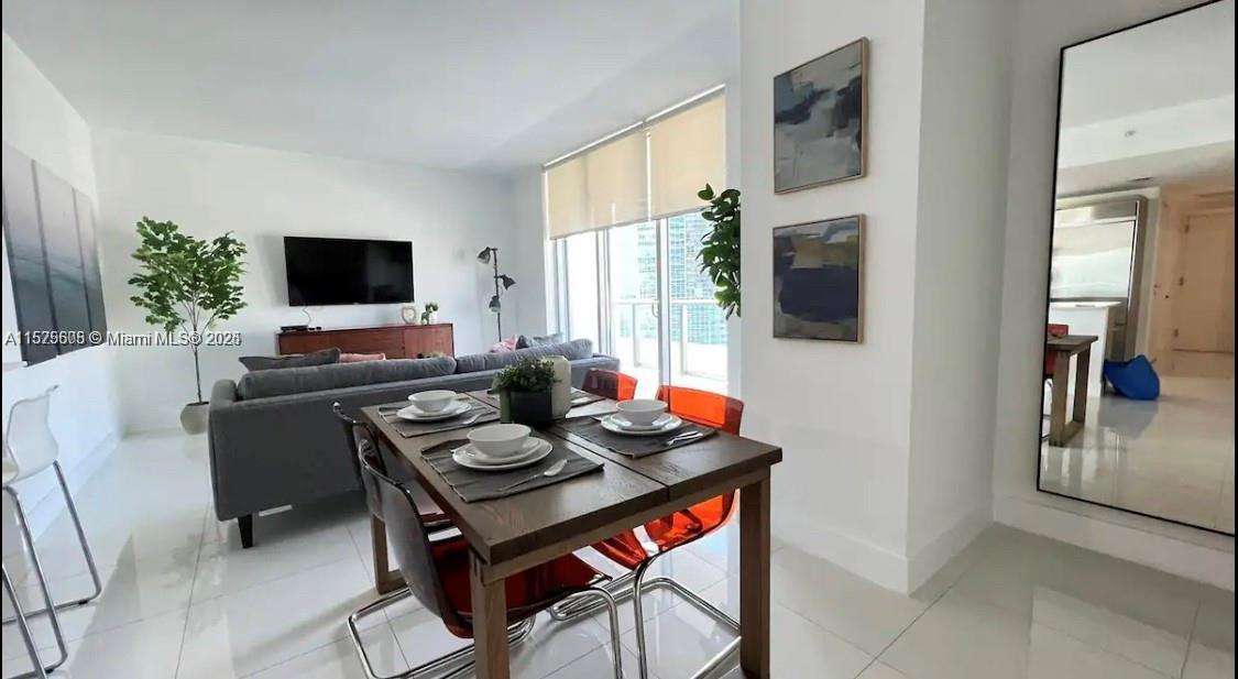 A dining area with a wooden table and orange chairs sits before a living room — 1300 BRICKELL BAY DR # 3400, Miami FL 33131, MIAMI, FL