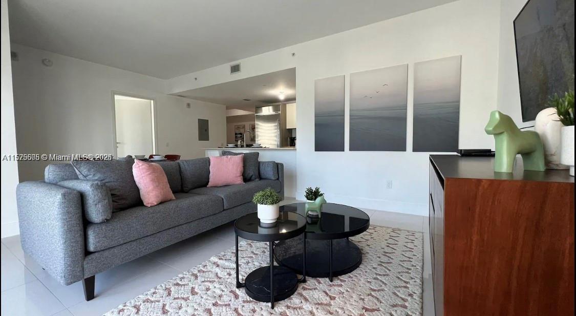 A living room features a grey sofa with pink pillows, a coffee table, and wall art — 1300 BRICKELL BAY DR # 3400, Miami FL 33131, MIAMI, FL