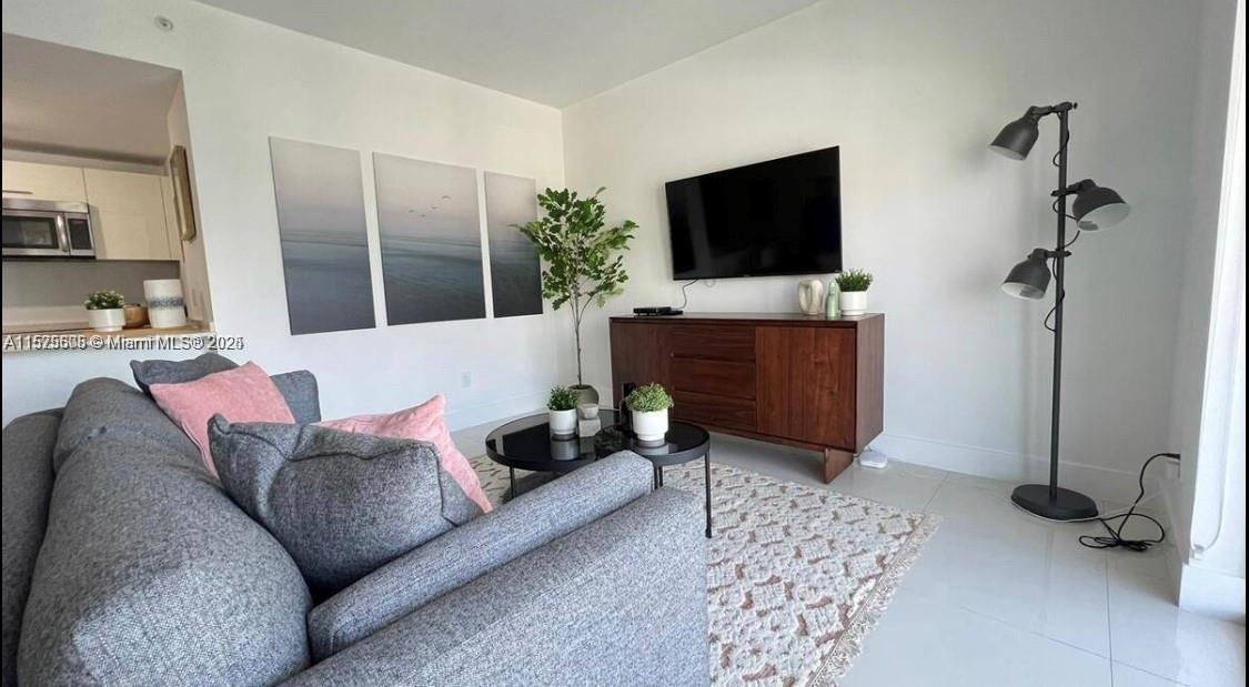 A living room features a grey sofa, a wooden media console, and a floor lamp — 1300 BRICKELL BAY DR # 3400, Miami FL 33131, MIAMI, FL