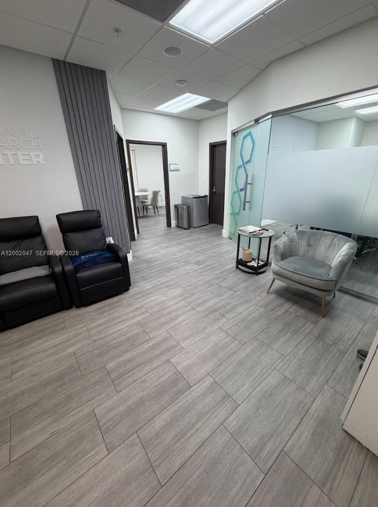 A waiting area features two black leather recliners, a grey armchair, and wood-look tile flooring — 8485 Bird Rd # 301, Miami FL 33155, MIAMI, FL