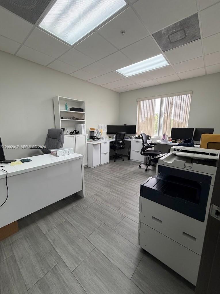 This office space features white desks, a tall bookshelf, a large printer, and wood-look flooring — 8485 Bird Rd # 301, Miami FL 33155, MIAMI, FL