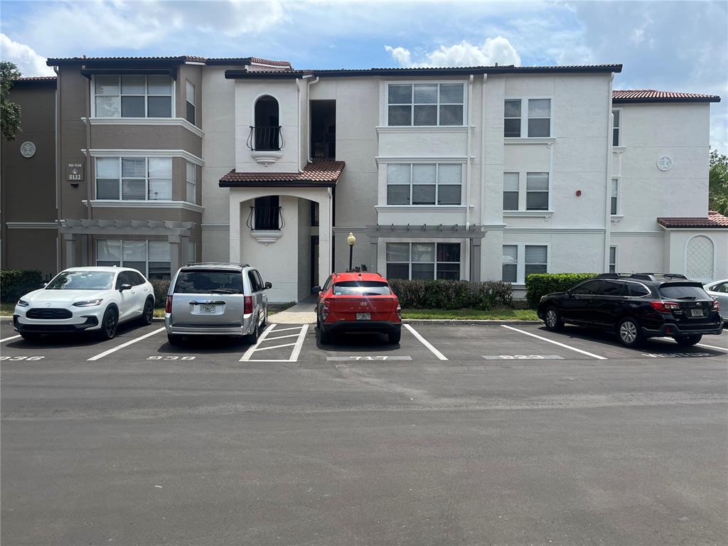 A three-story apartment building with a parking lot in front and four parked cars — 5132 CONROY ROAD UNIT 938, ORLANDO, FL