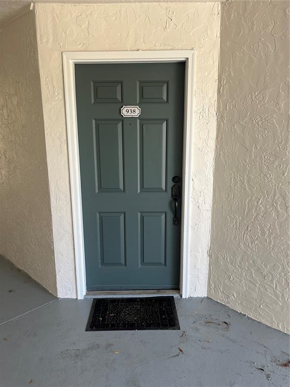A dark green front door with the number 938 is set in a textured wall — 5132 CONROY ROAD UNIT 938, ORLANDO, FL