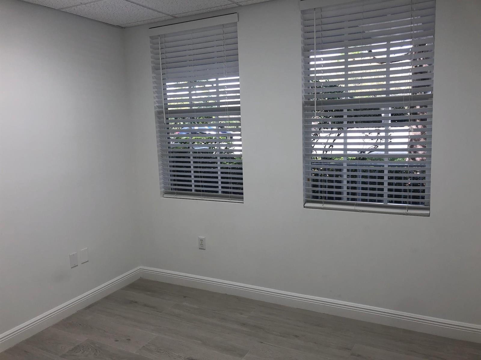 An empty room with white walls, wood-look flooring, and two windows with white blinds — 6958 Griffin Road # 9, Davie FL 33314, DAVIE, FL