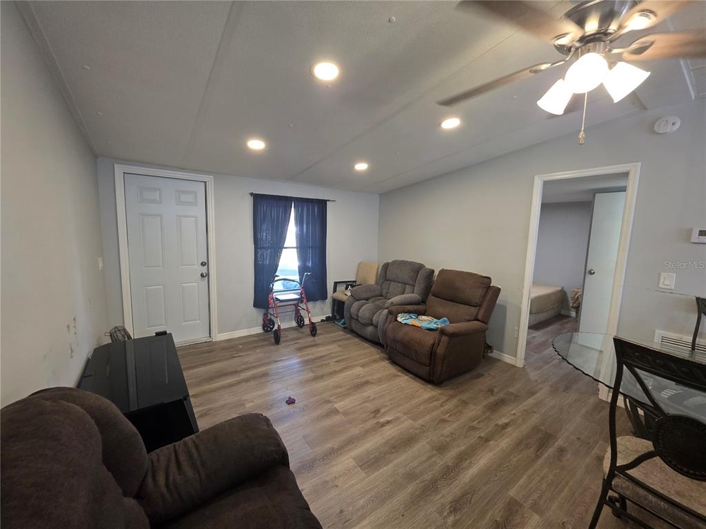 A living room with wood-look flooring, recessed lighting, a ceiling fan, and three recliners — 34924 TALISMAN STREET, DADE CITY, FL
