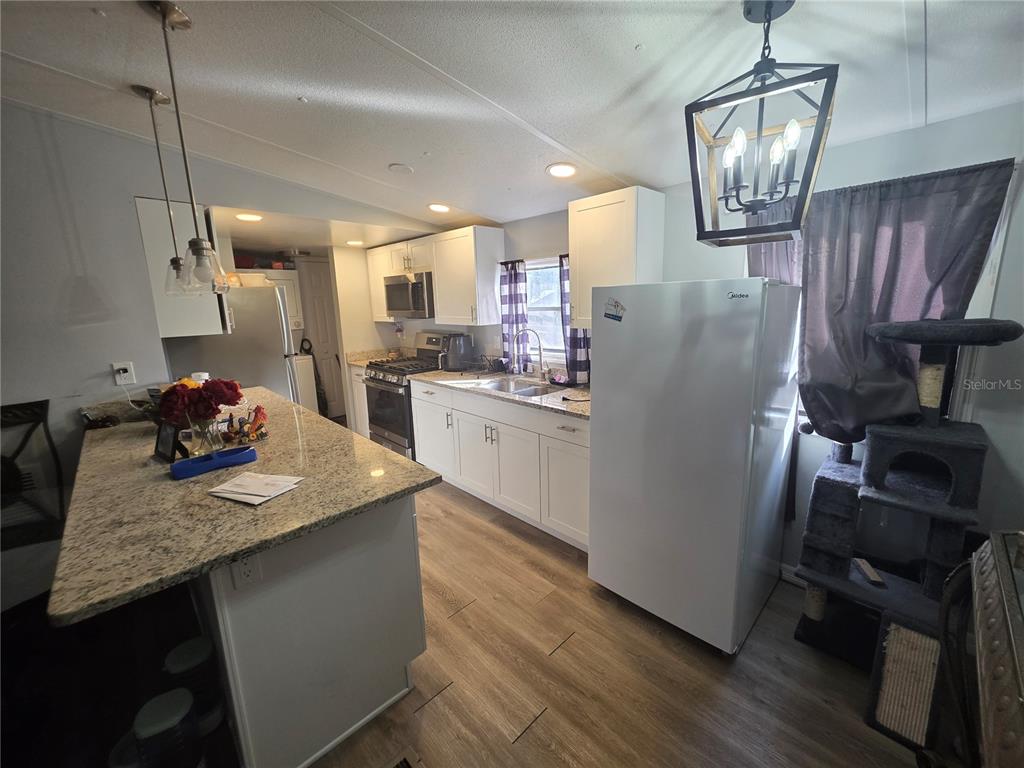 A kitchen features white cabinets, granite countertops, a large island, and a white refrigerator — 34924 TALISMAN STREET, DADE CITY, FL