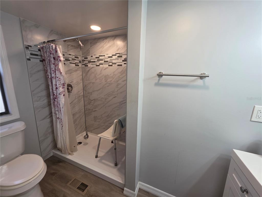 A bathroom features a walk-in shower with marble-look tile, a white vanity, and a toilet — 34924 TALISMAN STREET, DADE CITY, FL