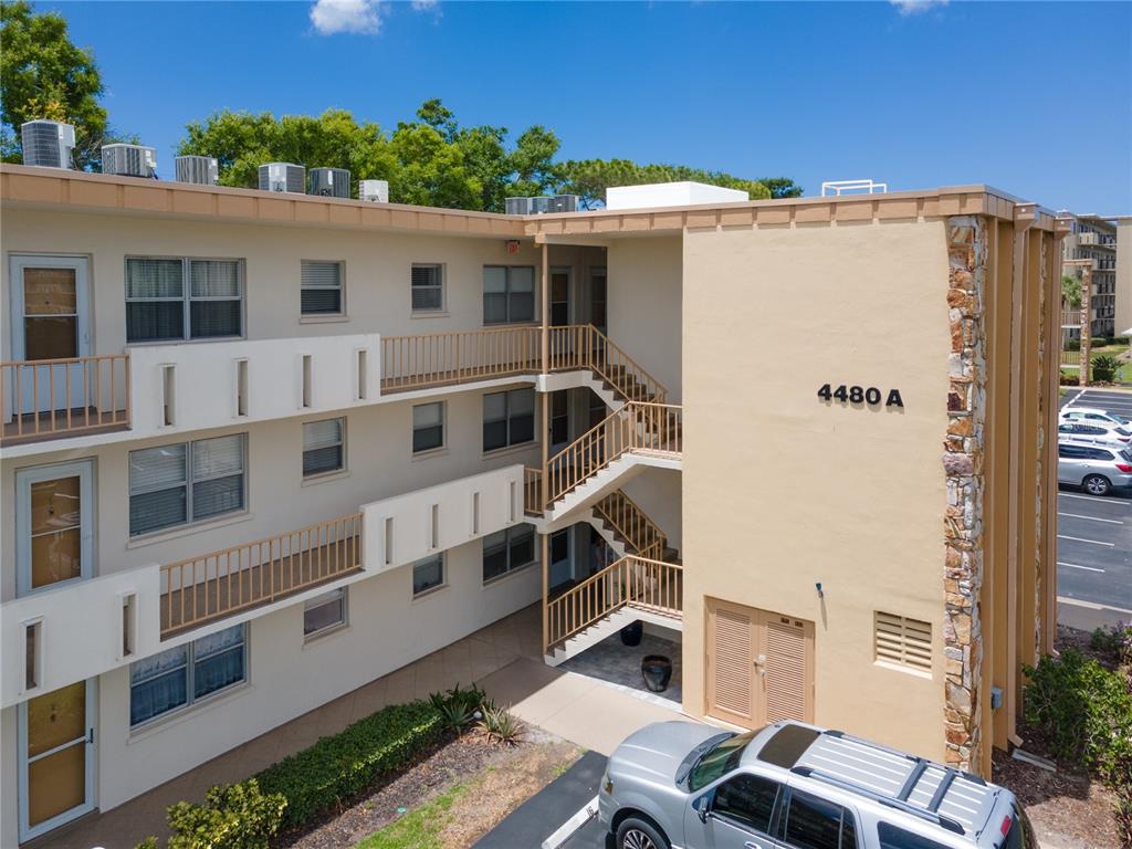 An exterior view of a three-story apartment building with tan stucco walls and metal stairs — 4480 IRONWOOD CIRCLE UNIT 309A, BRADENTON, FL