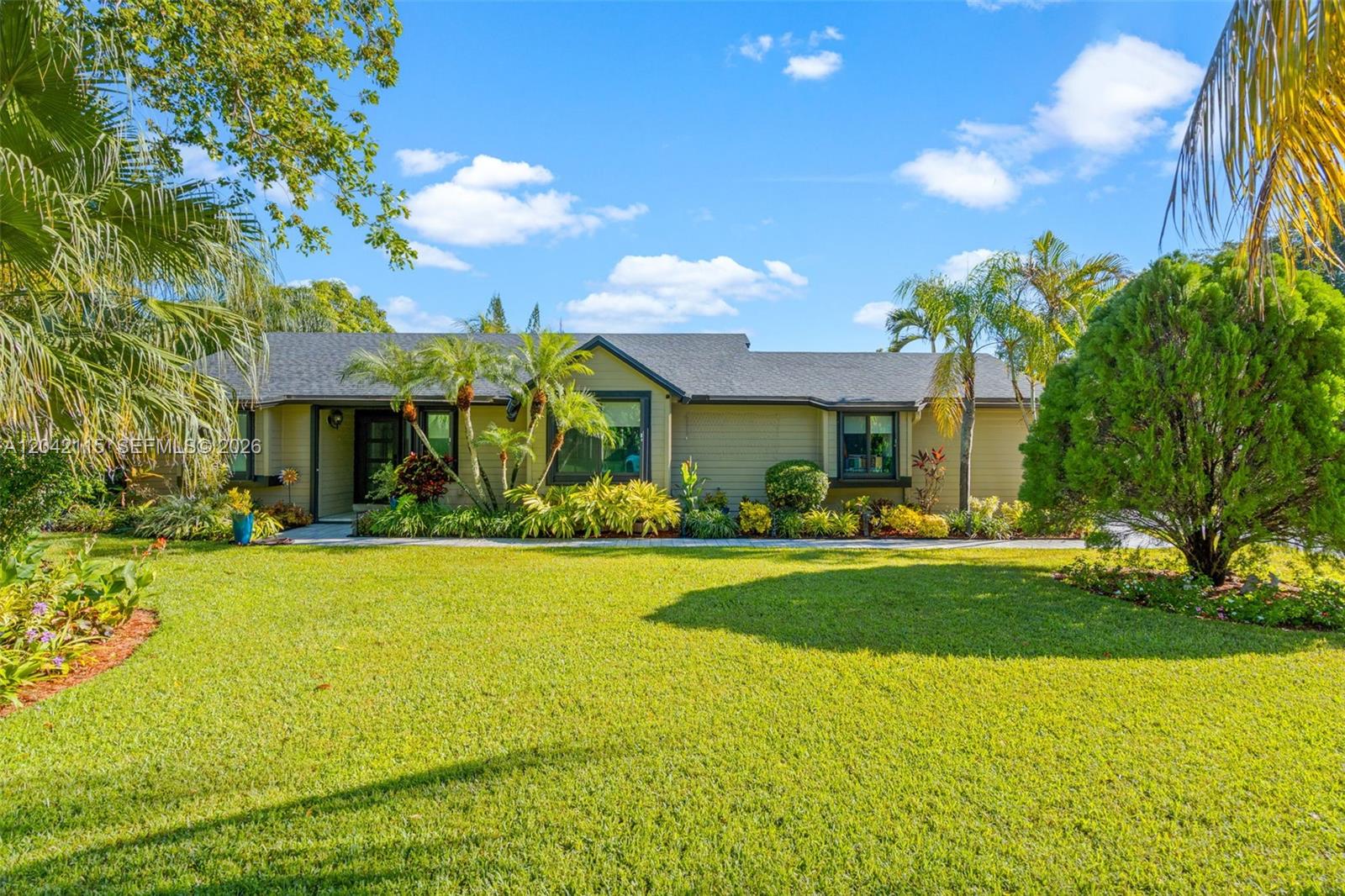 A single-story house with tan siding and a dark shingled roof sits behind a lawn — 15031 SW 154th Ter, Miami FL 33187, MIAMI, FL