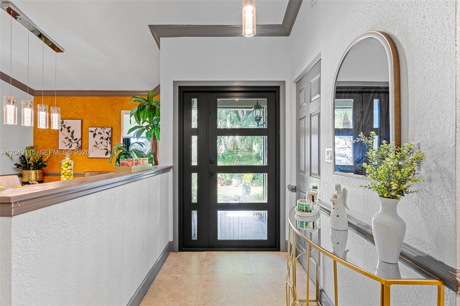 An entryway features a black glass-paneled door, a gold console table, and a yellow wall — 15031 SW 154th Ter, Miami FL 33187, MIAMI, FL